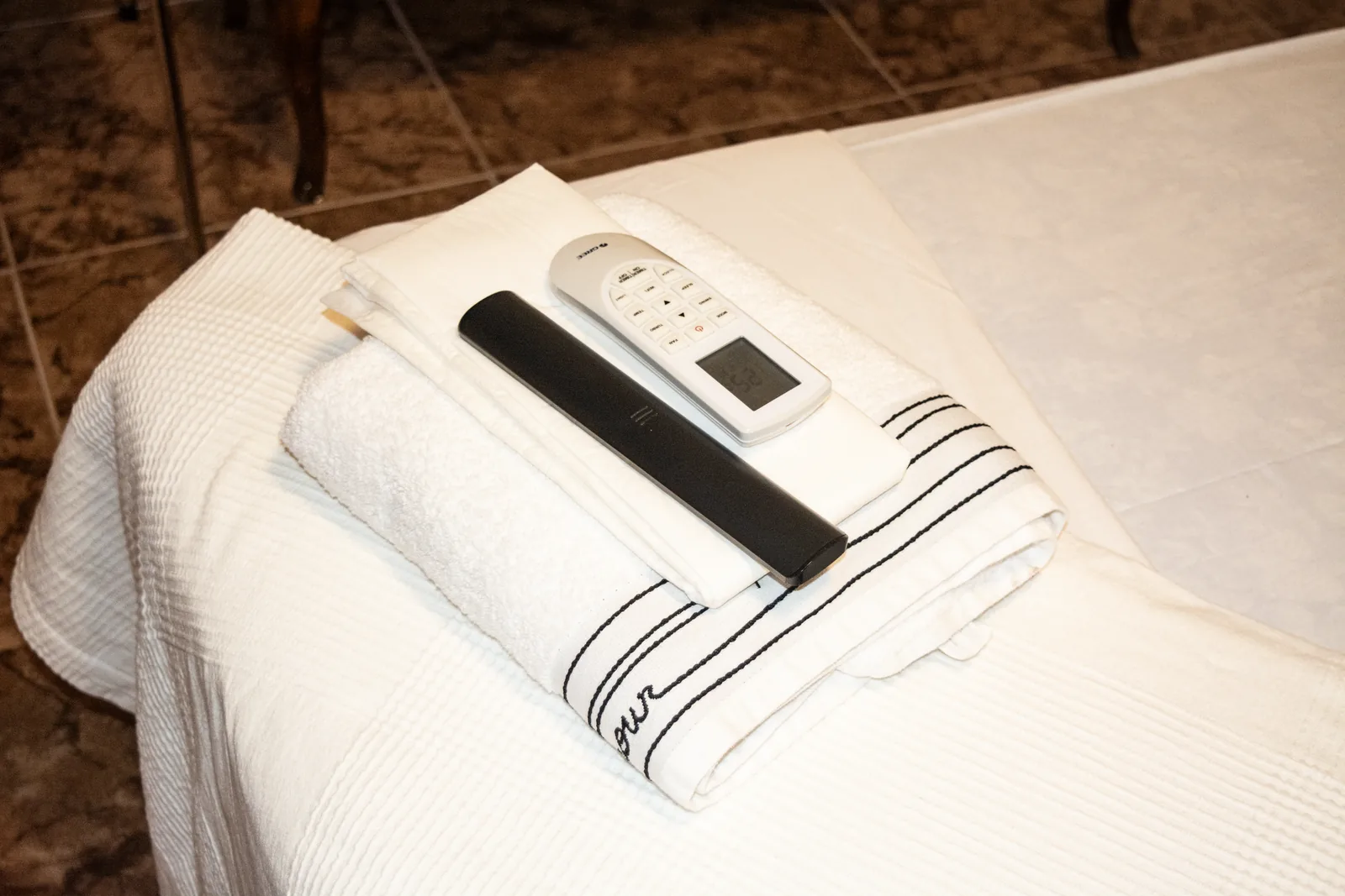 Toallas dobladas sobre la cama con mando de televisión