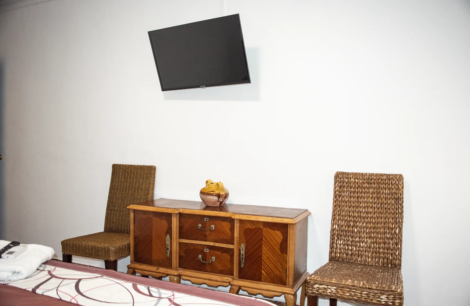 Habitación 104 con cama, televisor de pared y cómoda de madera