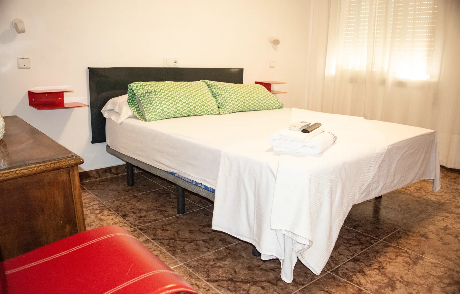 Habitación con cama, televisor y mesita en tonos rojos