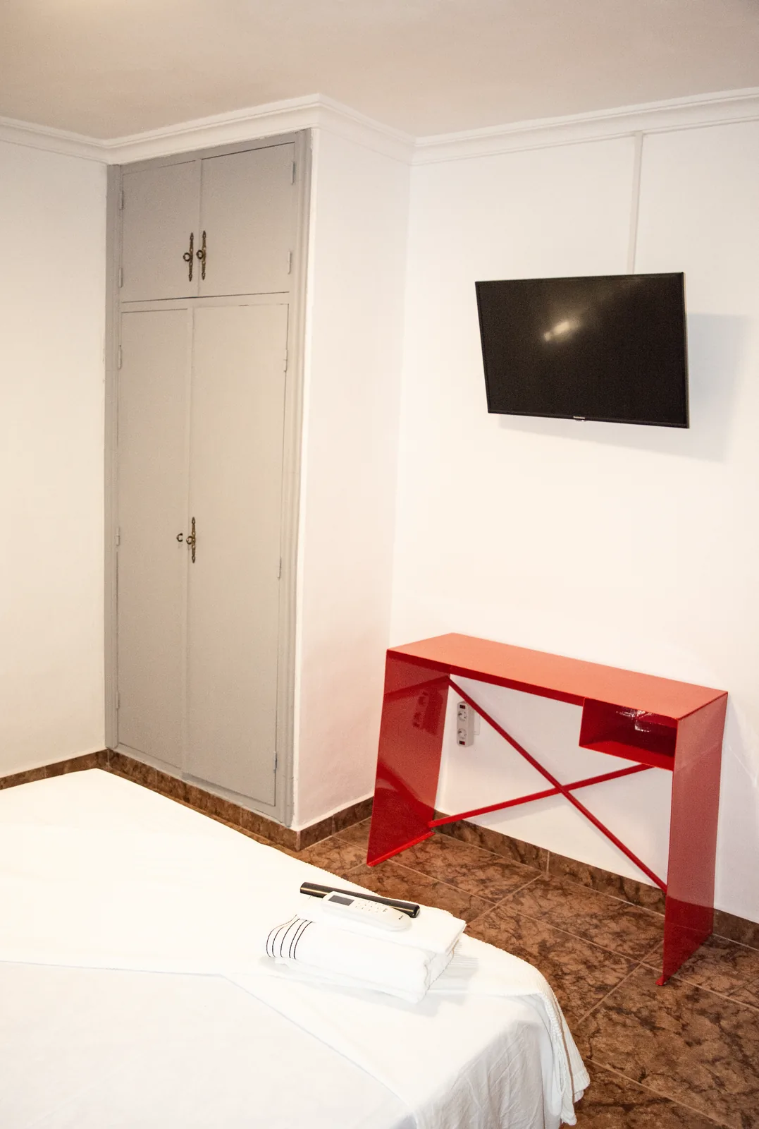 Habitación 105 con escritorio rojo y sillón de fibra